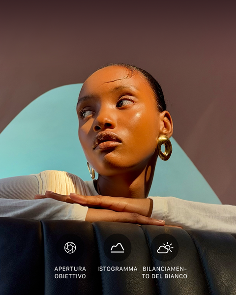 Primo piano di una persona ben illuminata su uno sfondo colorato, a mostrare l’interfaccia dei controlli professionali del sistema di fotocamere Pro: apertura dell’obiettivo, istogramma e bilanciamento del bianco